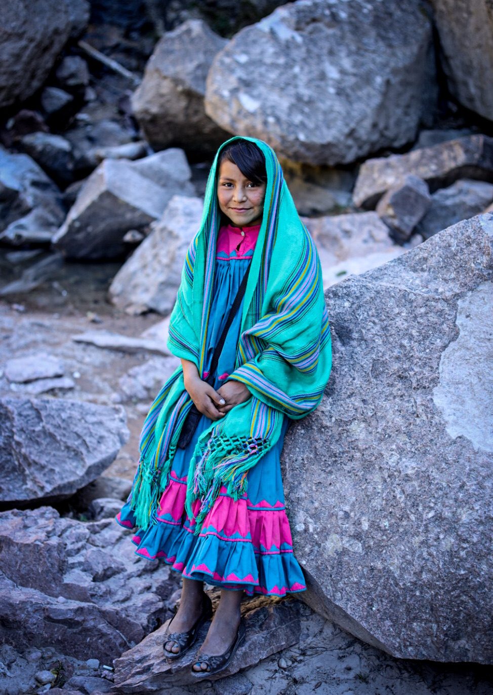 Niña con rebozo turquesa entre rocas